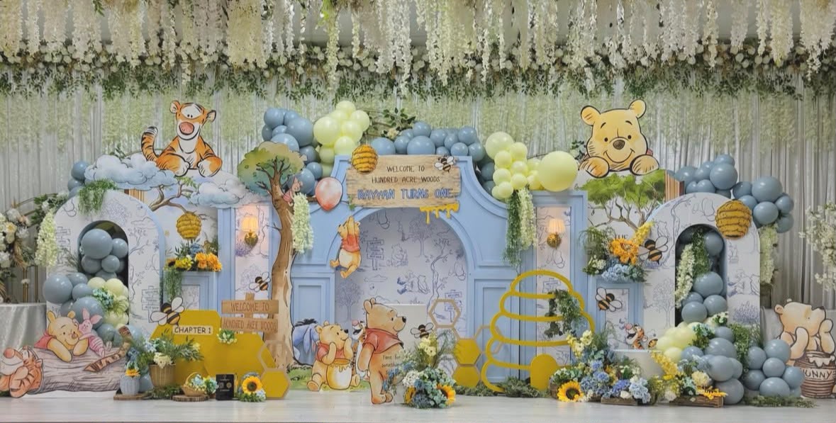 Winnie the Pooh hundred-acre woods thematic birthday stage styling with rustic wooden signs