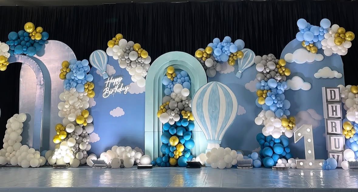 Pastel balloon arch with neon number milestone sign and delicate floral plinths
