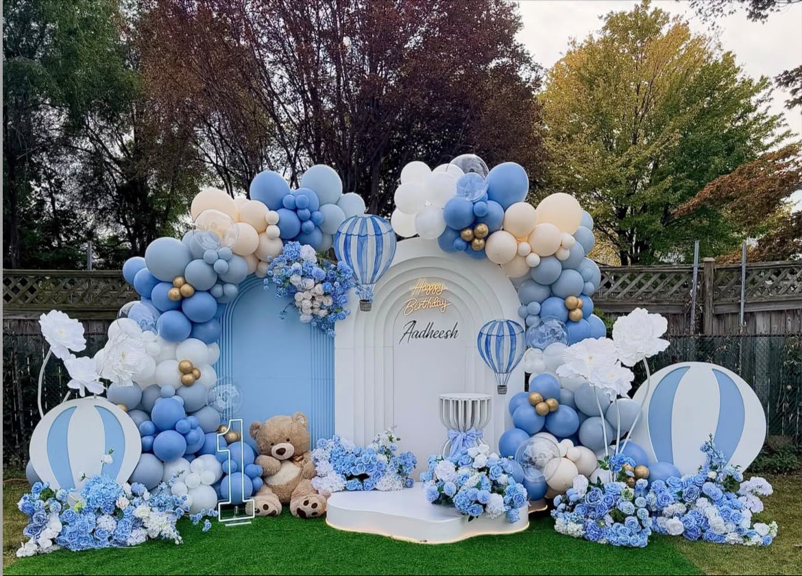 Soft pastel floral arches with organic balloon clouds and personalized backdrop signage