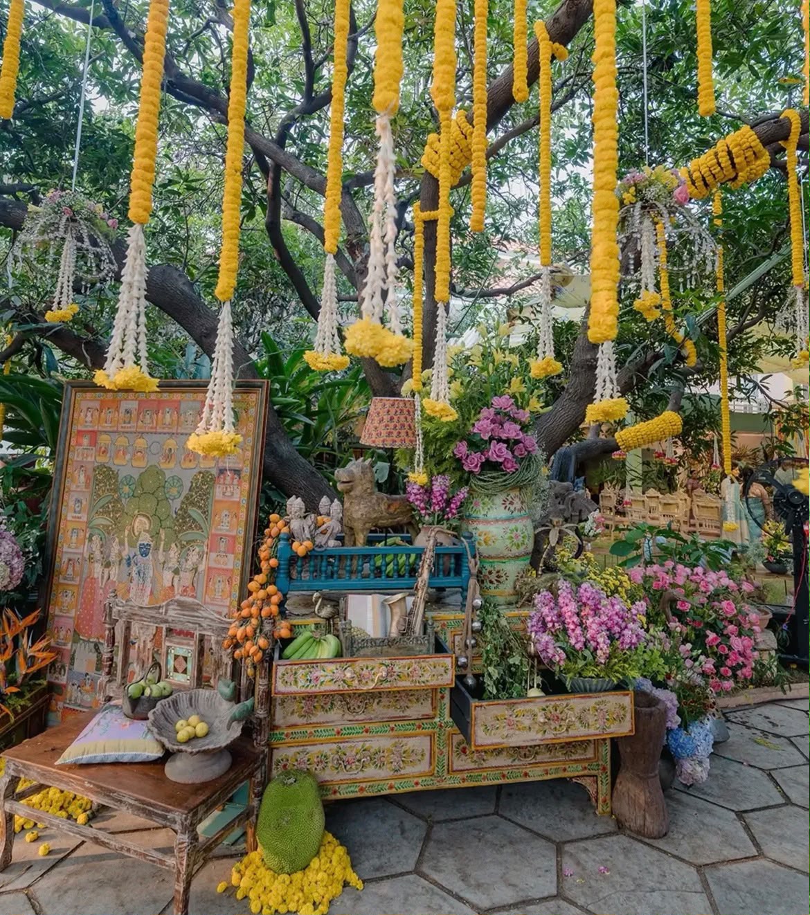 Lush open-air tree floral canopy with suspended floral strings and floor cushions