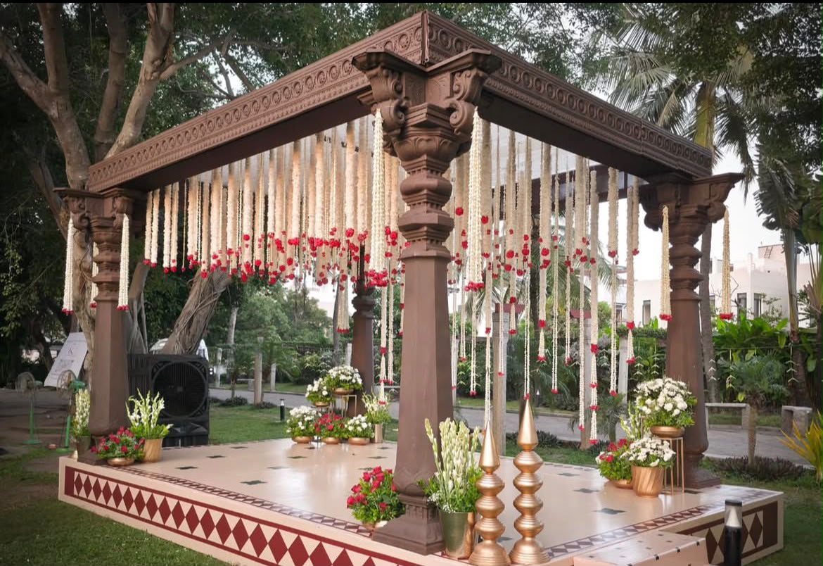 Traditional home ceremony setup with turmeric-yellow floral rangoli and brass urlis