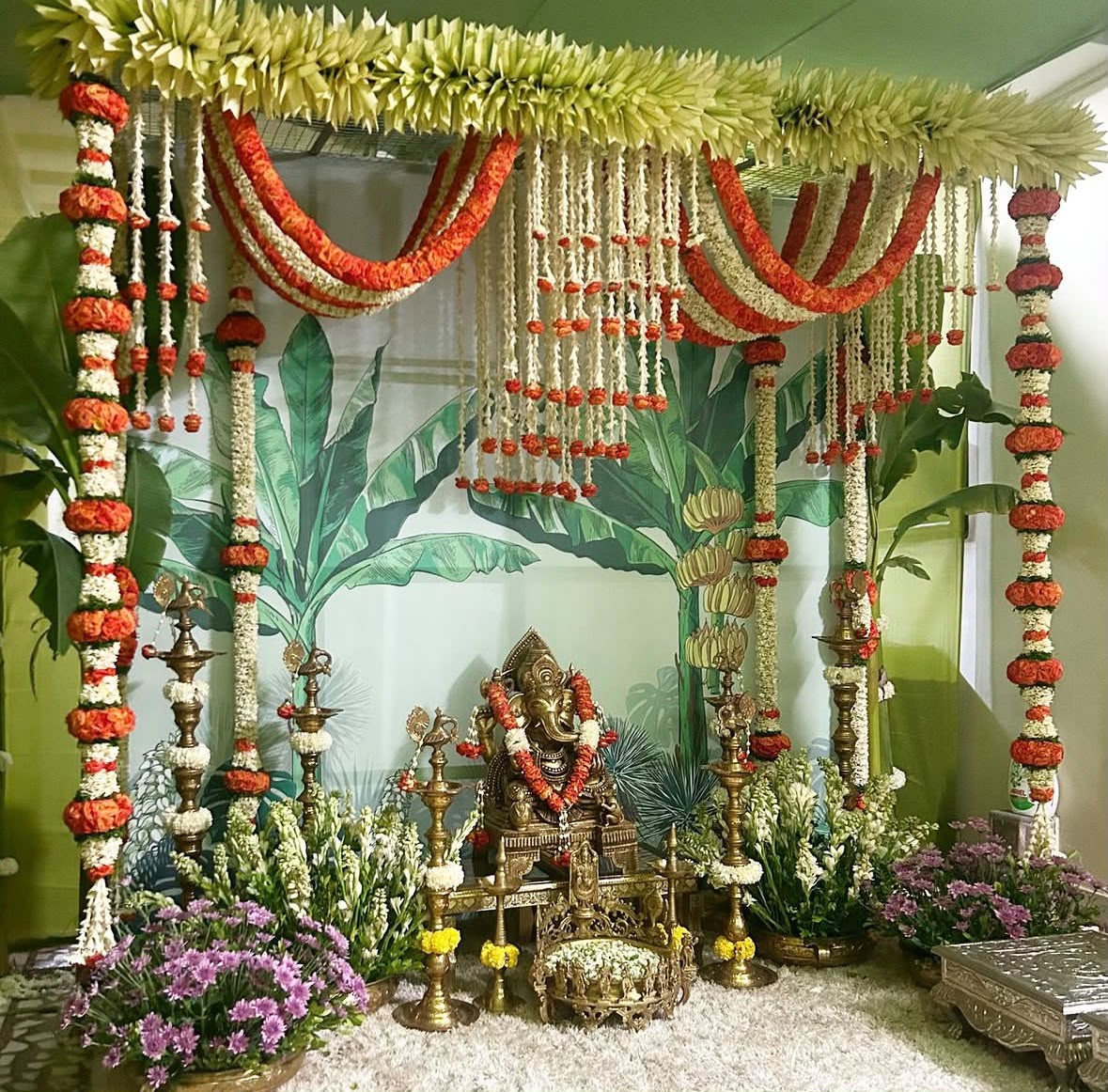 Living room festive pooja stage with traditional kalash, betel leaves, and flower garlands
