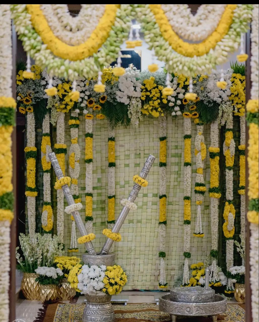 Intimate housewarming ceremony setup with auspicious doorway toran and floral pillars