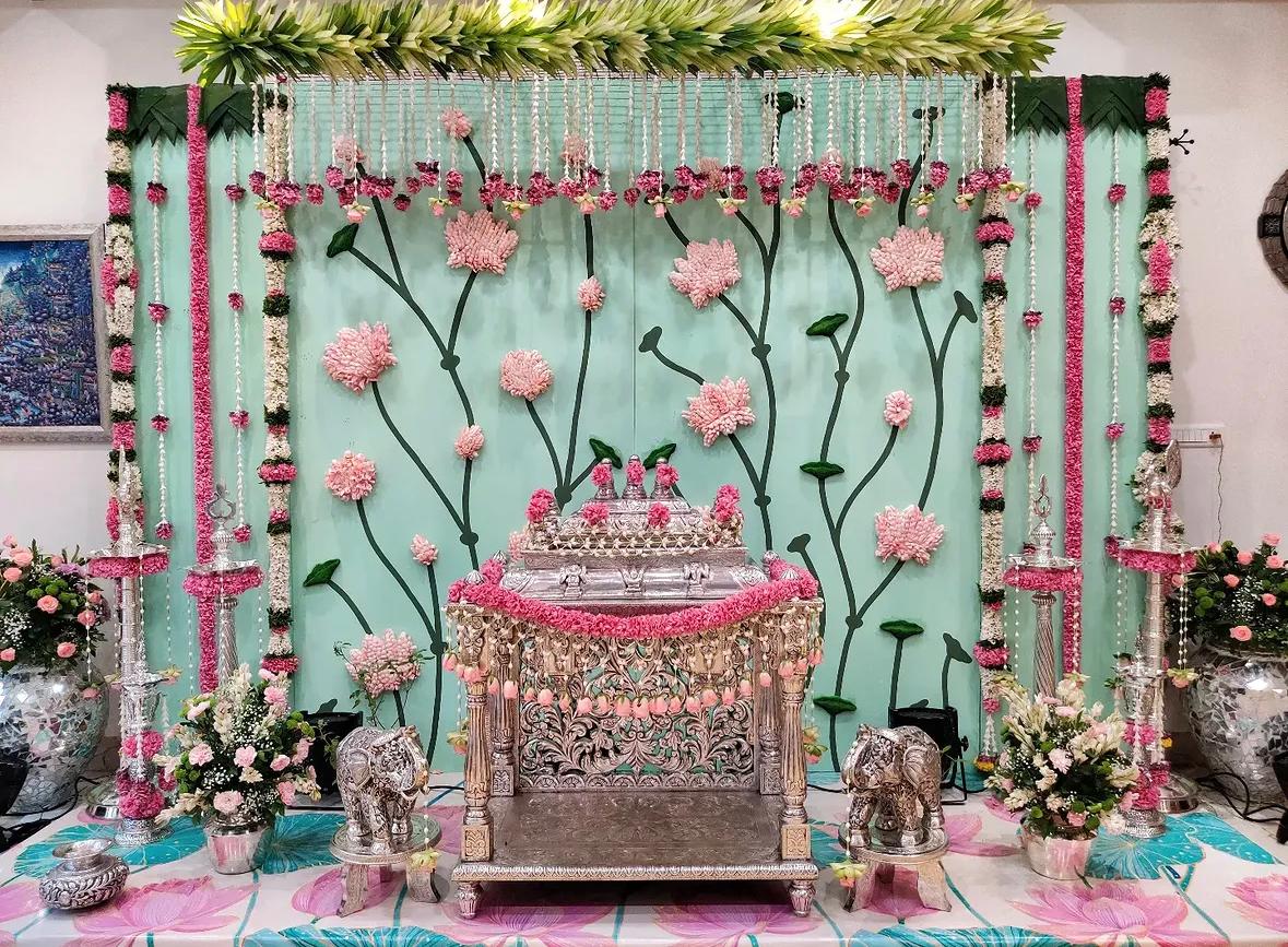 Traditional home celebration stage with handloom fabric backdrop and fresh rose wreaths