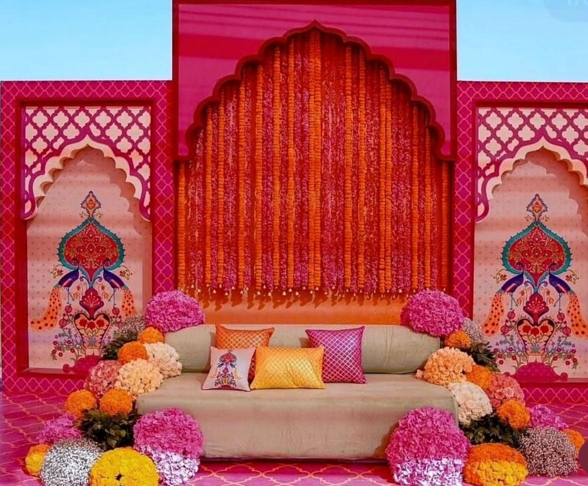 Royal pink and orange jali arch backdrop with intricate peacock art and marigold curtain for mehendi ceremony
