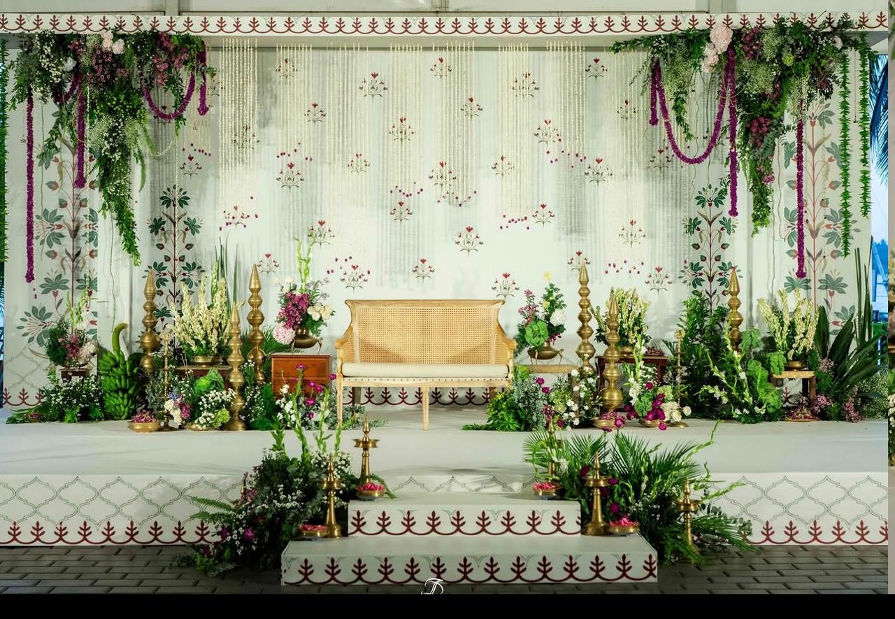 Elegant reception backdrop with cascading greenery, orchids, and warm architectural wash lights