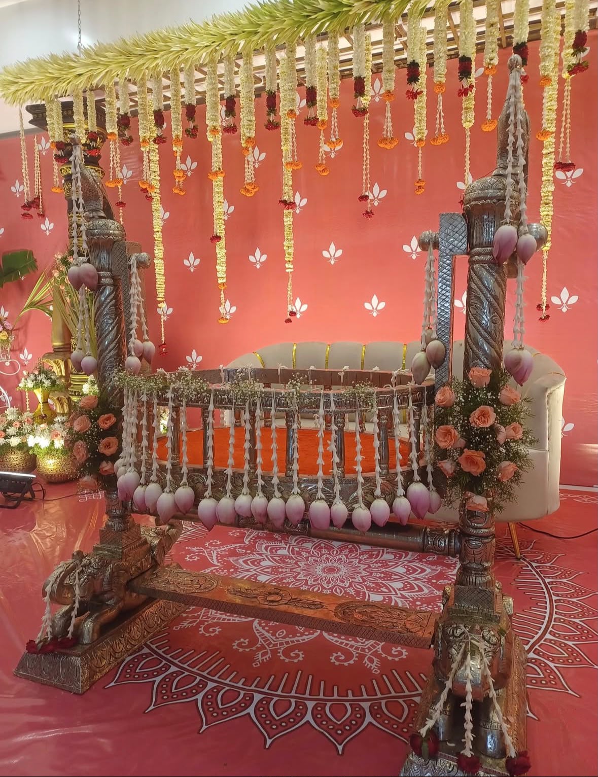 Heritage brass swing cradle ceremony adorned with lotus buds and marigolds