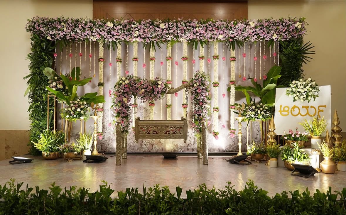 Sacred pooja stage with intricate rangoli, brass lamps, and hanging bell garlands