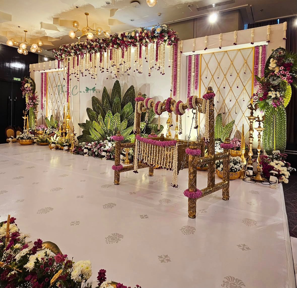 Grand temple mandap backdrop with classical wood-carved pillars and jasmine garlands