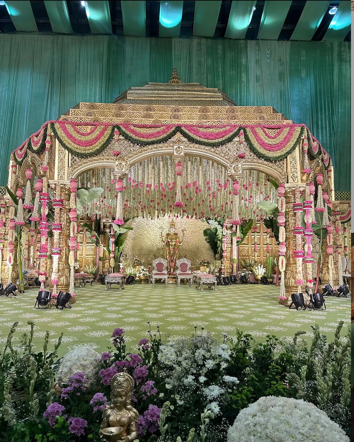 Regal temple mandap adorned with fresh rose garlands and Lord Ganesha idol