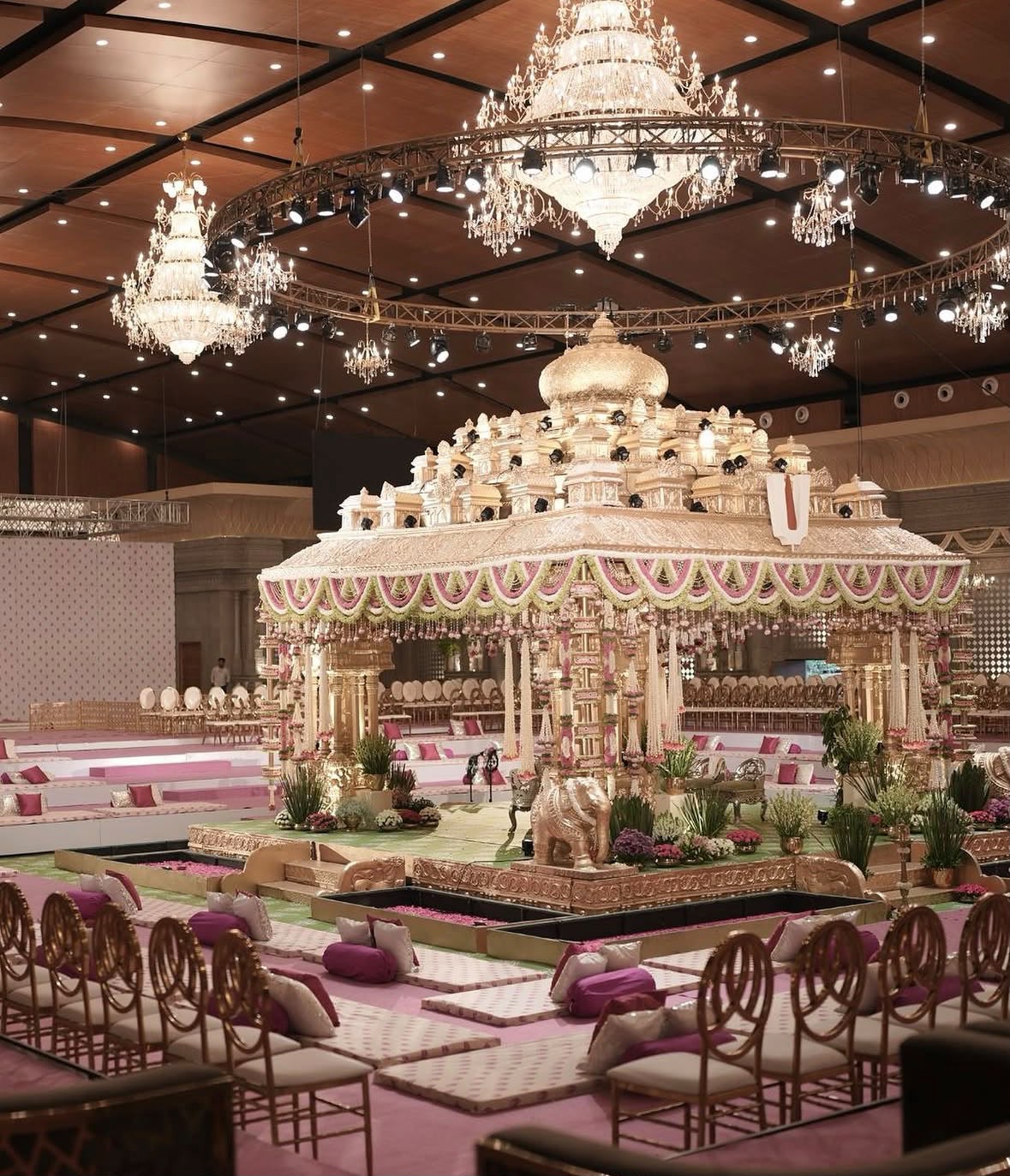Sophisticated wedding ceremony setting with pastel floral arches and brass deities