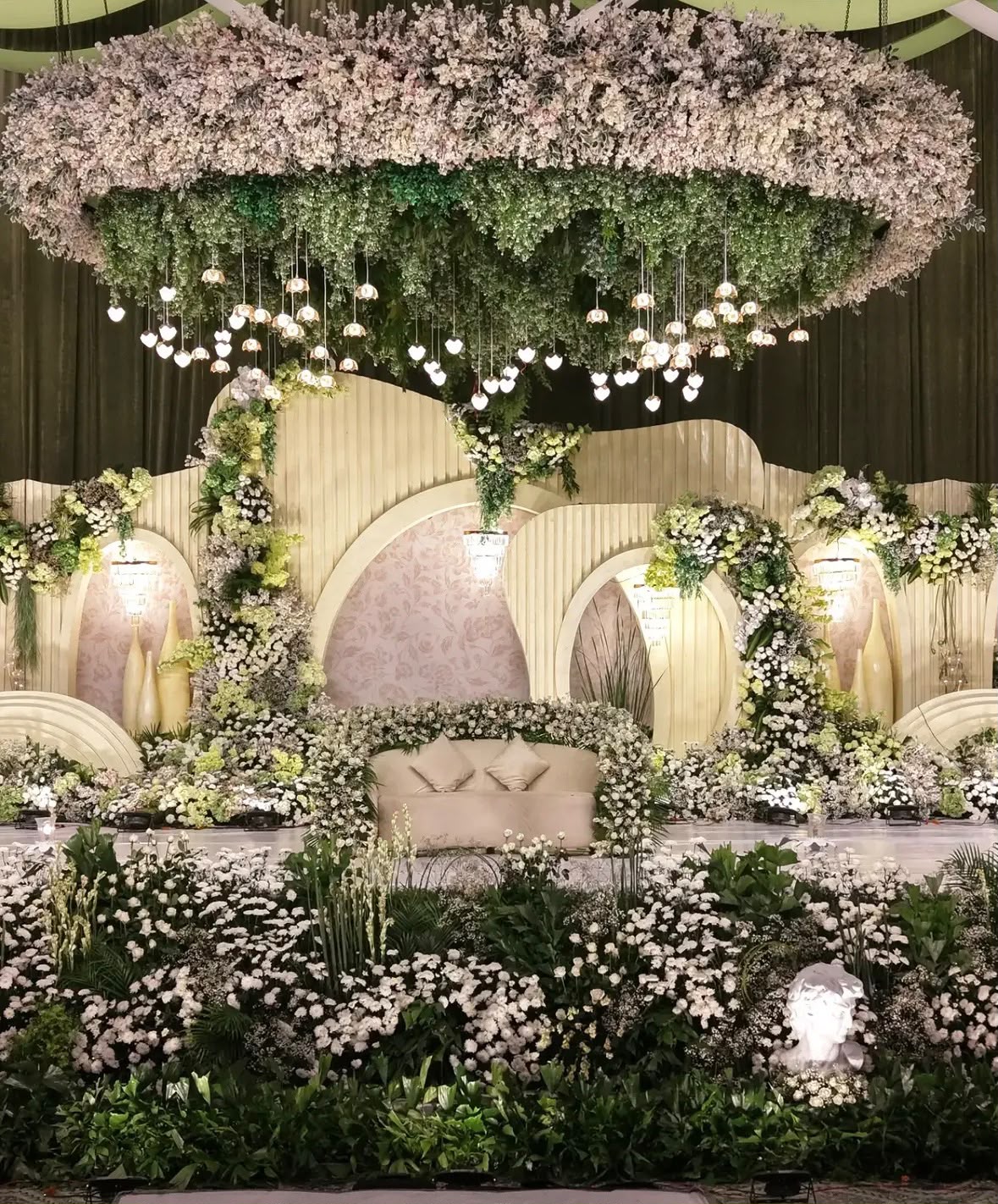 Golden carved wedding mandap with intricate jali pillars and floral torans