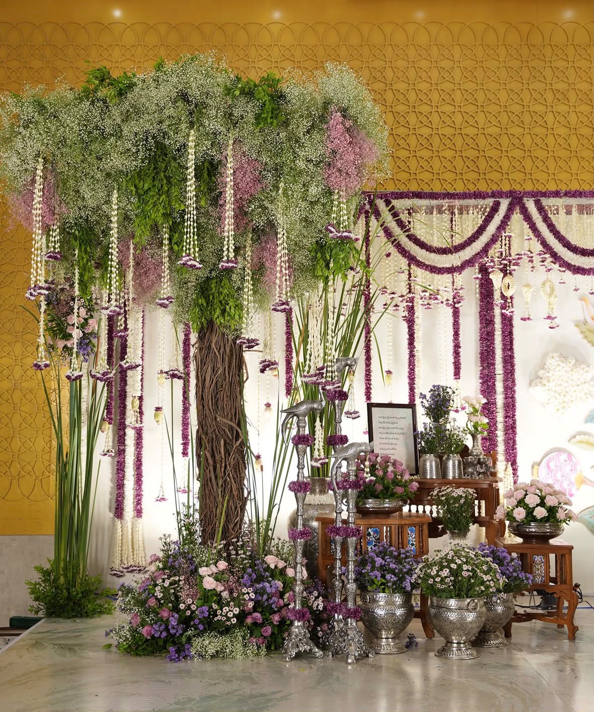 Sacred wedding mandap with brass Vishnu and Lakshmi deities and pink velvet chairs