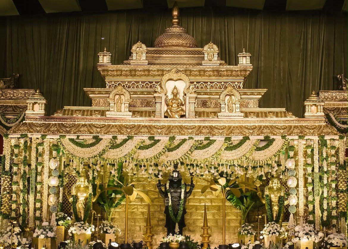 Artisanal wedding stage framing with golden peacock motifs and floral garlands
